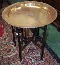 A Chinese hardwood folding centre table, the circular brass top profusely engraved with characters,