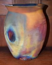 An earthenware ovoid raku vase, attributed to Willie Carter, in typical matt rainbow tones,