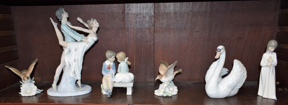 A Lladro model, as a swan; a Lladro figure, of bird hovering over a flower; another,