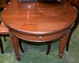 An Edwardian mahogany wind-out dining table, discorectangular shaped top above a deep frieze,