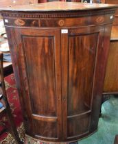 A George III mahogany bow-front corner cupboard,