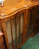 A 1940's walnut veneered serpentine display cabinet