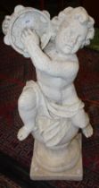 An 18th century style composition garden statue, of a scantily clad putto playing a tambourine,