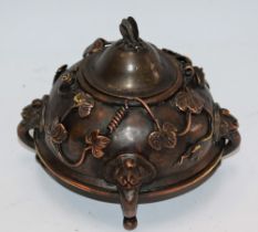 An Oriental bronze censor, applied with scrolling vines, the lid with butterfly finial,