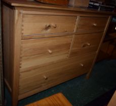 A contemporary light oak chest, oversailing rectangular top above an arrangement of drawers,