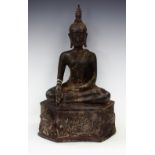 A Tibetan bronze Buddha, modelled seated above a mask head cushion,