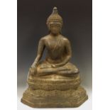 A Tibetan bronze Buddha, modelled seated above maskhead, floral base,