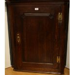 A George III oak corner cabinet, with arched fielded panelled door, shaped shelves, 96cm high,
