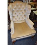 A George III wingback armchair, deep button backed, pale gold upholstery, c.