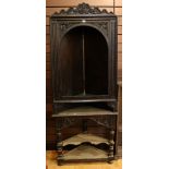 A 18th century dark oak open front floor standing corner cupboard, carved top,