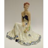 A Royal Dux figure of an elegant lady, she sits facing to the right,