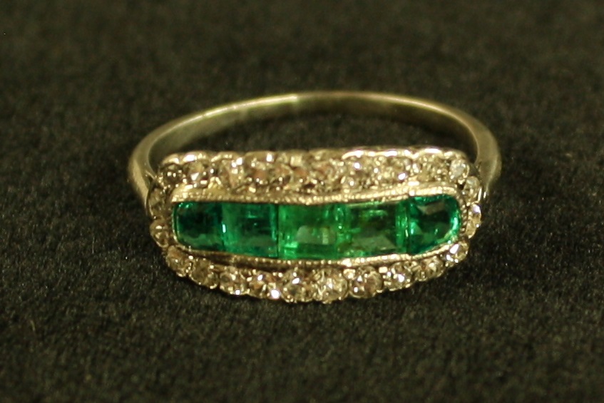 An emerald and diamond cluster ring, central crest of five old irregular and cushion cut emeralds,