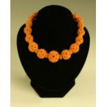 A carved graduated pink bead necklace, possibly coral, composed of carved globular floral beads,