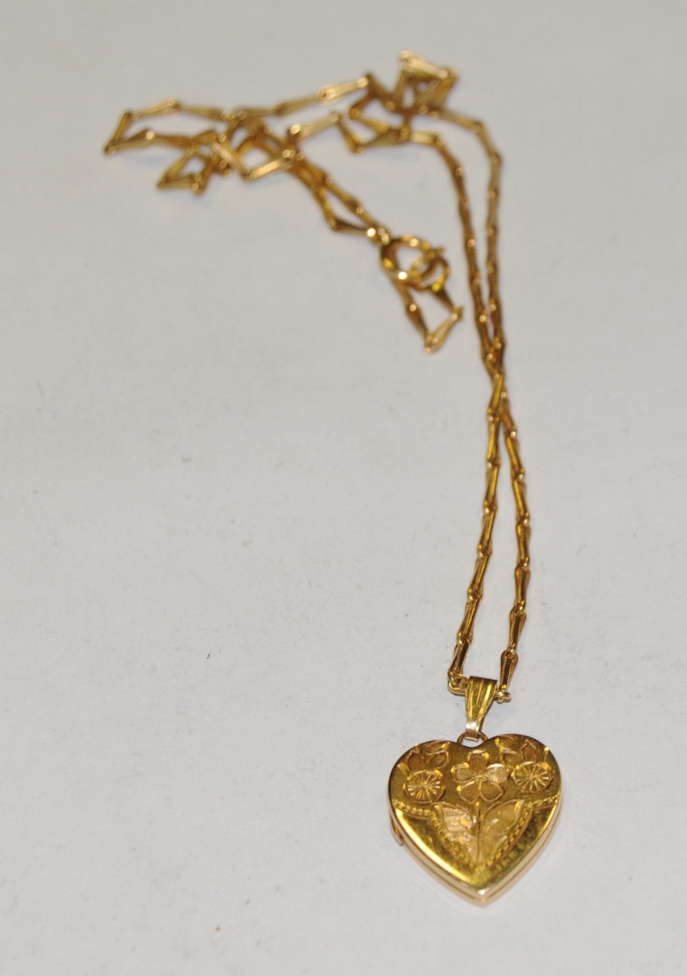 A 14ct gold heart locket pendant, suspended from an 18ct gold fancy link chain necklace, 6.