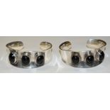 A pair of amethyst inset silver bangles, each with three slightly irregular oval amethyst cabochons,