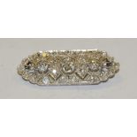 An Art Deco platinum and diamond bar brooch, open case panel inset with twenty nine oval,