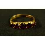 An Edwardian garnet quintet line ring, graduated crest of red garnets, scrolling mount,