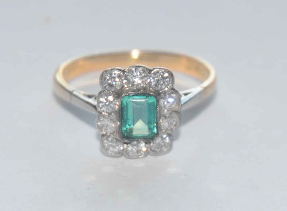 An emerald and diamond cluster ring, central rectangular baguette cut emerald approx 0.