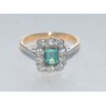 An emerald and diamond cluster ring, central rectangular baguette cut emerald approx 0.