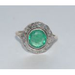 An emerald and diamond cluster ring, central round cut emerald approx 2.