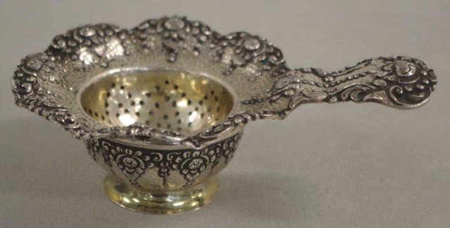Silver tea strainer on stand