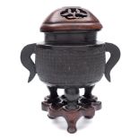 A small Chinese bronze tripod censer: of oval form with flattened scroll handles,