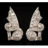 A pair of early 20th century diamond earrings: of scroll ribbon design with graduated old,