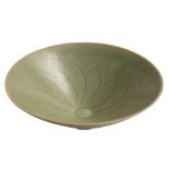 A Chinese celadon bowl: of flared conical form, the interior carved with a stylised lotus flower,
