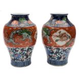 A pair of Japanese Imari baluster vases: painted predominantly in underglaze blue,