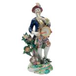 A Bow figure of a musician: wearing a plumed hat, blue jacket and floral breeches,