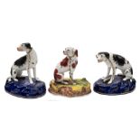 A pair of English porcelain models of hounds and one other: the pair with black markings,