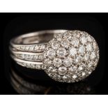 An 18ct white gold and diamond mounted oval bombe cluster ring: the raised oval cluster between