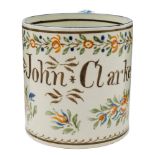 A Bovey Tracey pearlware mug: inscribed 'John Clarke' and decorated in blue, brown,