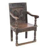 A 17th Century carved stained elm open armchair:, the panelled back with arcaded,