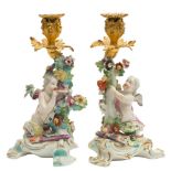A pair of Derby gilt-metal mounted cupid candlesticks: one holding a heart, the other a bow,