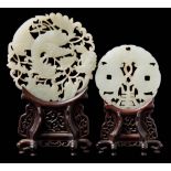 Two Chinese carved and pierced celadon jade discs: the larger in the form of a phoenix amongst