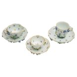 A group of three Meissen floral encrusted cabinet cups and saucers: with entwined stalk handles,