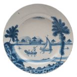 A Bristol blue and white delftware dish: painted with a coastal landscape with buildings, boats,