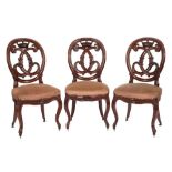A set of four Victorian carved mahogany dining chairs:, the oval moulded backs with crown,