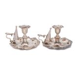 A pair of silver plated chambersticks: with urn-shaped nozzles and scroll borders,