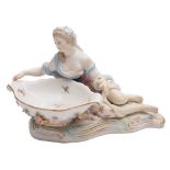 A Meissen figural sweetmeat dish: the shaped bowl applied with flowers and supported by a reclining