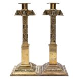 A pair of Middle Eastern brass candlesticks: with cylindrical nozzles and cruciform capitals on