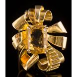 A cushion-shaped citrine single-stone brooch: of stylised ribbon scroll design,