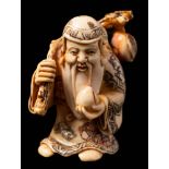 A Japanese carved ivory and stained netsuke depicting a Sennin: in traditional costume holding a