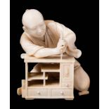 A Japanese carved ivory okimono of a carpenter,
