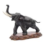 An early 20th century Japanese bronze model of a charging elephant: with faux ivory tusks and