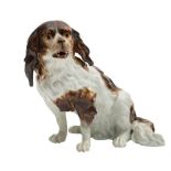 A late 19th century Continental porcelain figure of a spaniel: with shaggy coat and dark brown