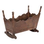 An 18th Century oak cradle:, of rectangular shape with tapered and serpentine topped sides,