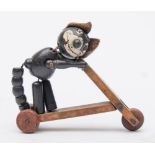 An early 20th century wooden Felix the Cat articulated figure riding a scooter,