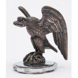 An eagle car mascot:, with raised wings seated on a rocky plinth,